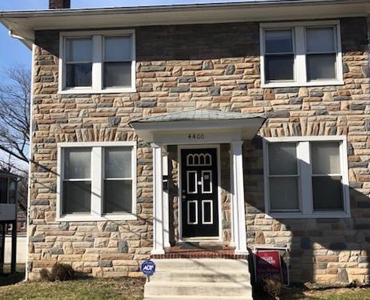 Stone house with black front door and white-framed windows.