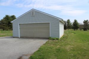A detached two-car garage with a closed door and a driveway.