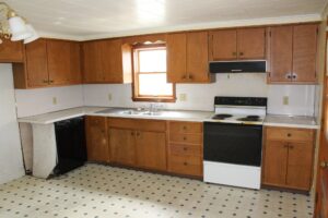 A kitchen with wooden cabinets, white appliances, and tiled flooring.