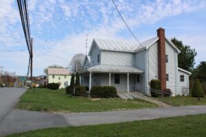 A gray two-story house with a covered porch and a chimney.