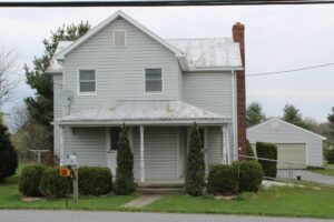A two-story gray house with a metal roof and a small porch.