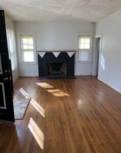 Empty room with hardwood floors and a fireplace.