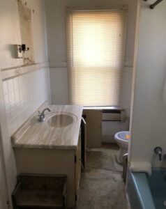 Small bathroom with a sink, toilet, and window covered by blinds.