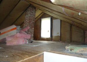 Insulated attic space with exposed brick chimney and wooden beams.