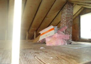 Insulation materials placed near a chimney in an attic space.