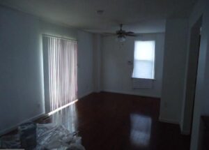 Empty room with hardwood floors, a ceiling fan, and window coverings.