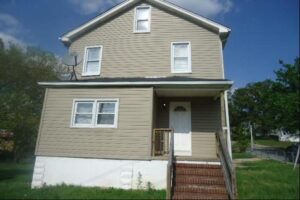 Two-story beige house with white trim and a small porch.