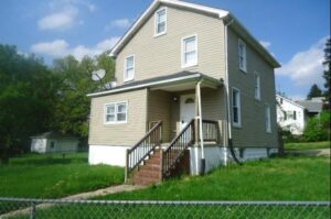 Two-story beige house with a small porch and stairs.