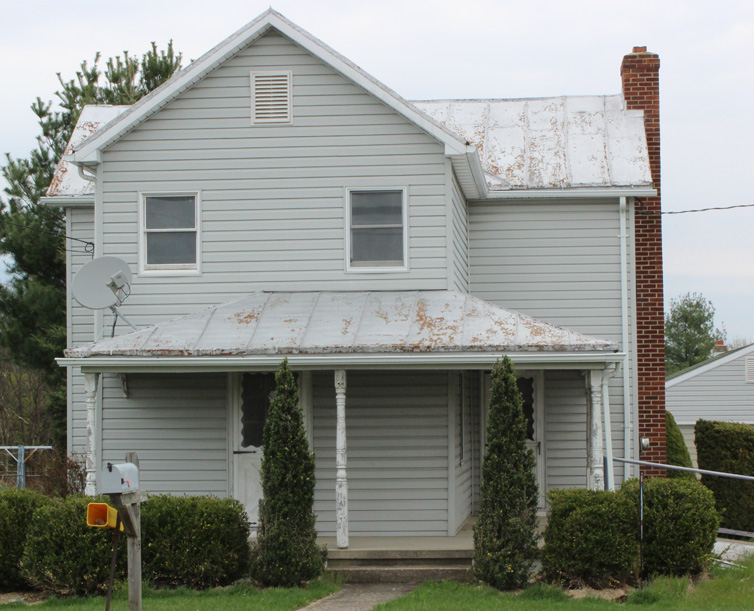 A two-story gray house with a metal roof and a covered porch.